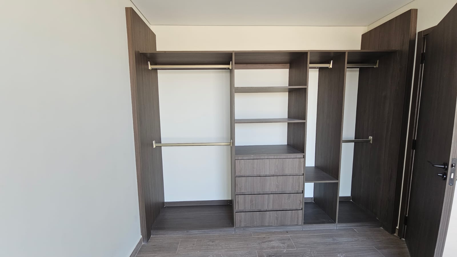 Clóset modular de recámara con dobles tubos de colgado, entrepaños y cajonería en acabado madera