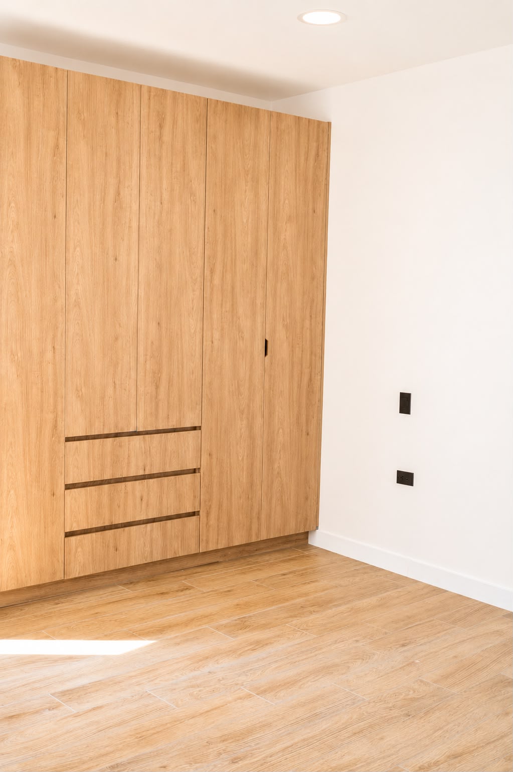 Clóset de piso a techo en madera clara con cajonería de tirador integrado