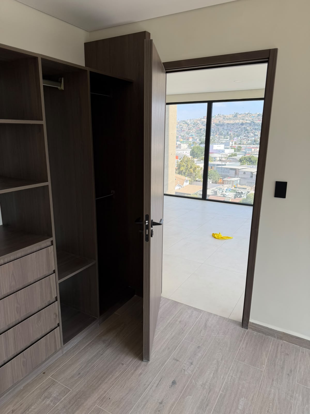 Recámara con clóset abierto y puerta hacia sala con ventanal de piso a techo