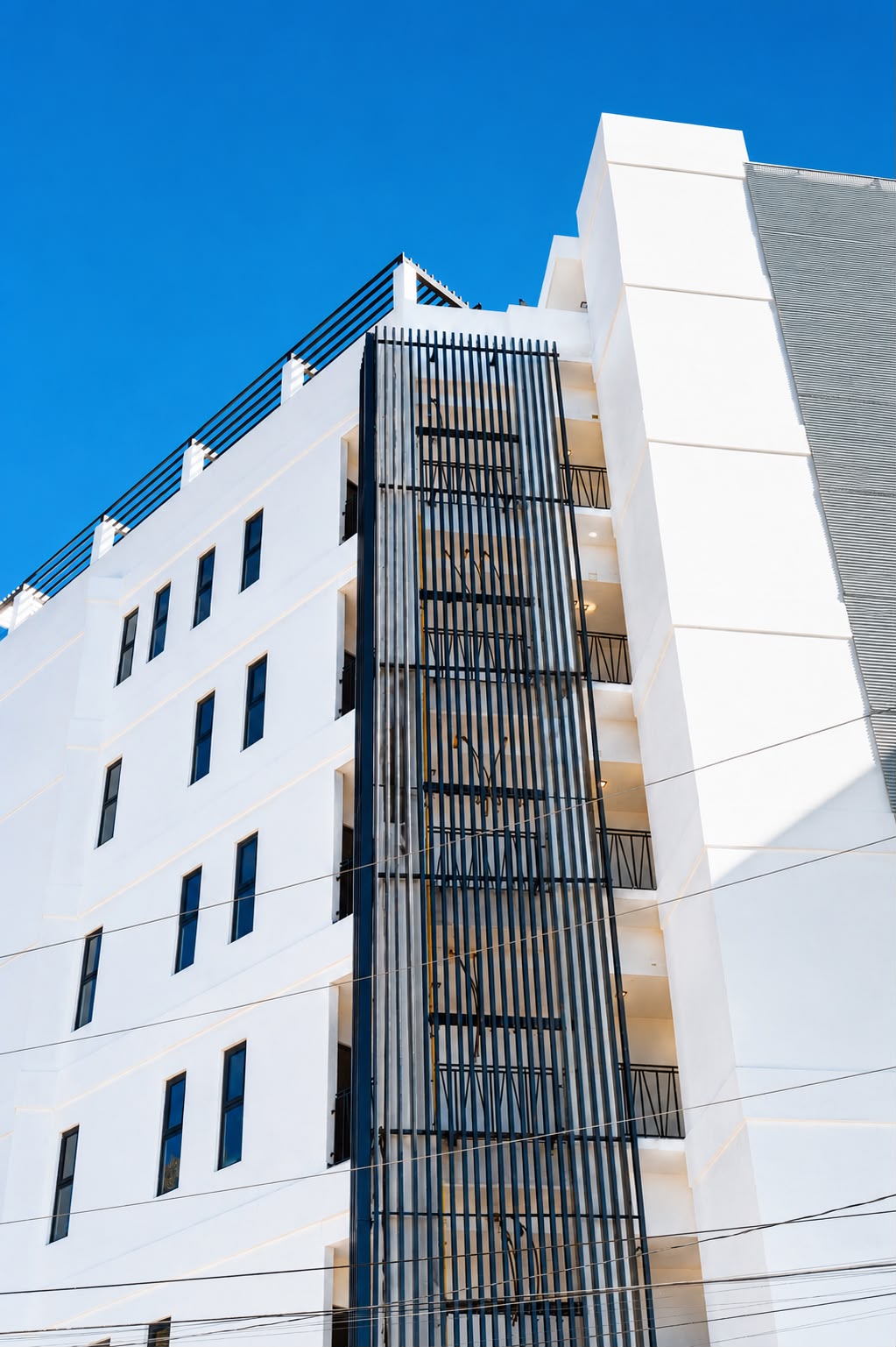 Fachada blanca de Colina Park con celosía metálica vertical en Tijuana